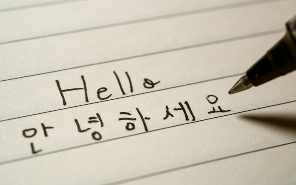 Korean language learner writing Hello word Annyeonghaseyo in Korean on a notebook