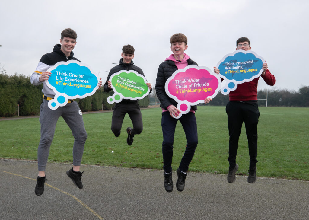 Students jumping in the air holding #ThinkLanguages signs